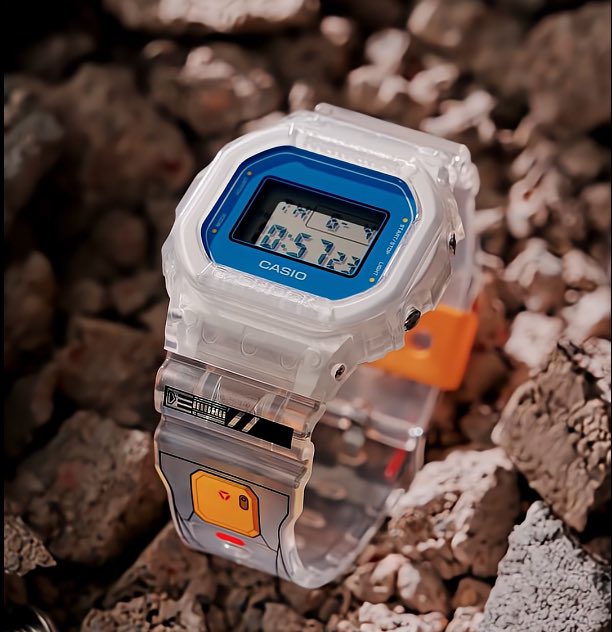 The transparent resin construction puts the Gundam-inspired blue bezel and E.F.S.F. branding front and center.