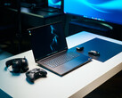 Razer Blade 18 2026 gaming laptop setup on a white desk with glowing RGB keyboard, mouse, gaming controller, and headphones in a dark studio setting.