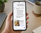 A hand holding a smartphone showing an AI answer with a sponsored ad below it