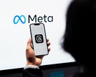 A hand holds a smartphone in front of a large Meta logo