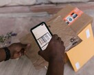A hand holds a smartphone over a parcel and scans its barcode