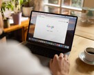 Person at a laptop with the Google homepage open, next to a cup of coffee