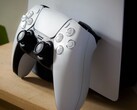 A picture of a PlayStation 5 DualSense controller leaning against a PS5 console