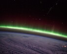 A photo taken from the ISS showing a green auroral arc above the clouds