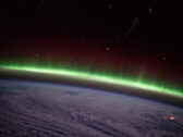 A photo taken from the ISS showing a green auroral arc above the clouds