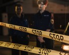 Two police officers standing at night behind a yellow tape that reads Stop