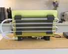DIY liquid-cooled MacBook Neo setup with external radiator and tubing attached to the laptop