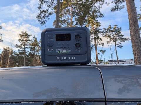 Bluetti Elite 100 V2 Bio-based on a car roof with pine trees in the background