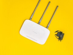 White Wi-Fi router with three antennas and a power supply on a yellow background