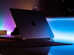 Half-open MacBook in a dark room, light spilling from the gap onto the desk