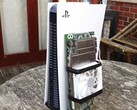 A PlayStation 5 console placed beside a custom-built AMD BC250 board mounted with a heatsink and cooling fan. (Image source: Budget-Builds Official via YouTube)